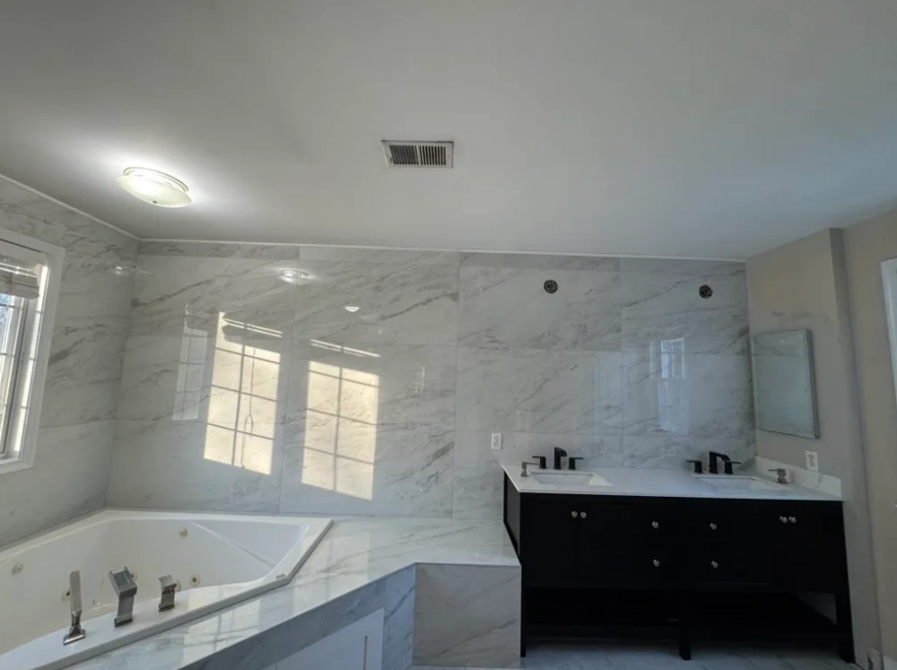 Walk-in shower with white marble-look large tiles and matte black rain showerhead and niche in a new BeltLine townhome in Old Fourth Ward